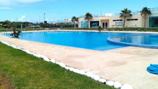 Une grande piscine extérieure, avec un ciel bleu clair en arrière-plan.