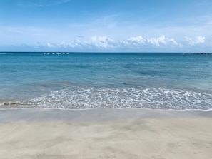 A beach with clear blue water, gentle waves, and a sandy shore. - Modern beach apartment / near airport (Carolina)