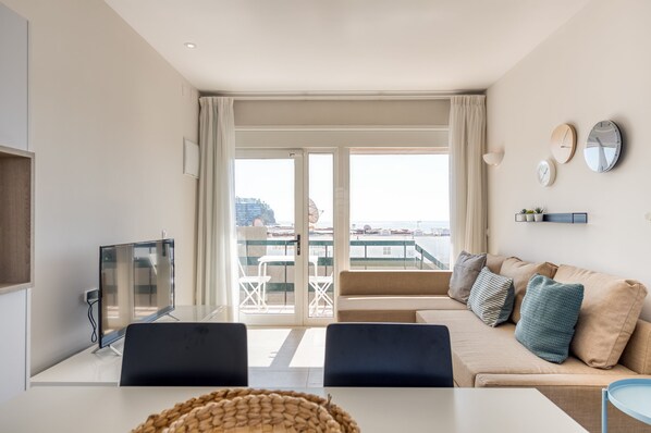 Een moderne woonkamer met een bank, een televisie en een balkon met uitzicht op de stad.