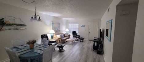 En stue med spiseplads, en sofa, et sofabord og et tv-møbel.