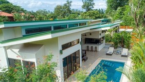 A modern two-story house with a large balcony, a swimming pool, and outdoor seating. - New Luxury Home, private pool! 300 steps to beach, 8 min. walk to bars & dining (Dominical de OSA)