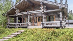 Eine Blockhütte mit Veranda, Holzwegen und freiem Blick auf den umliegenden Wald.