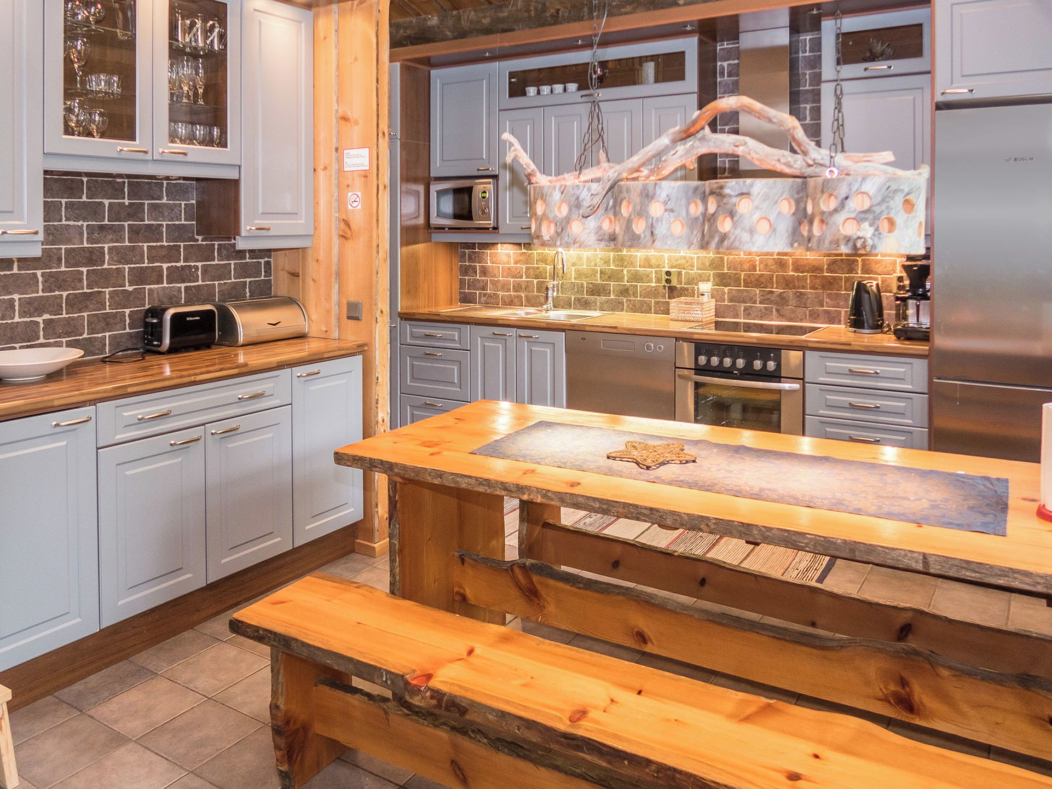 A modern kitchen with grey cabinets, a wooden island, and a built-in microwave.