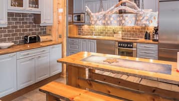 A modern kitchen with grey cabinets, a wooden island, and a built-in microwave.