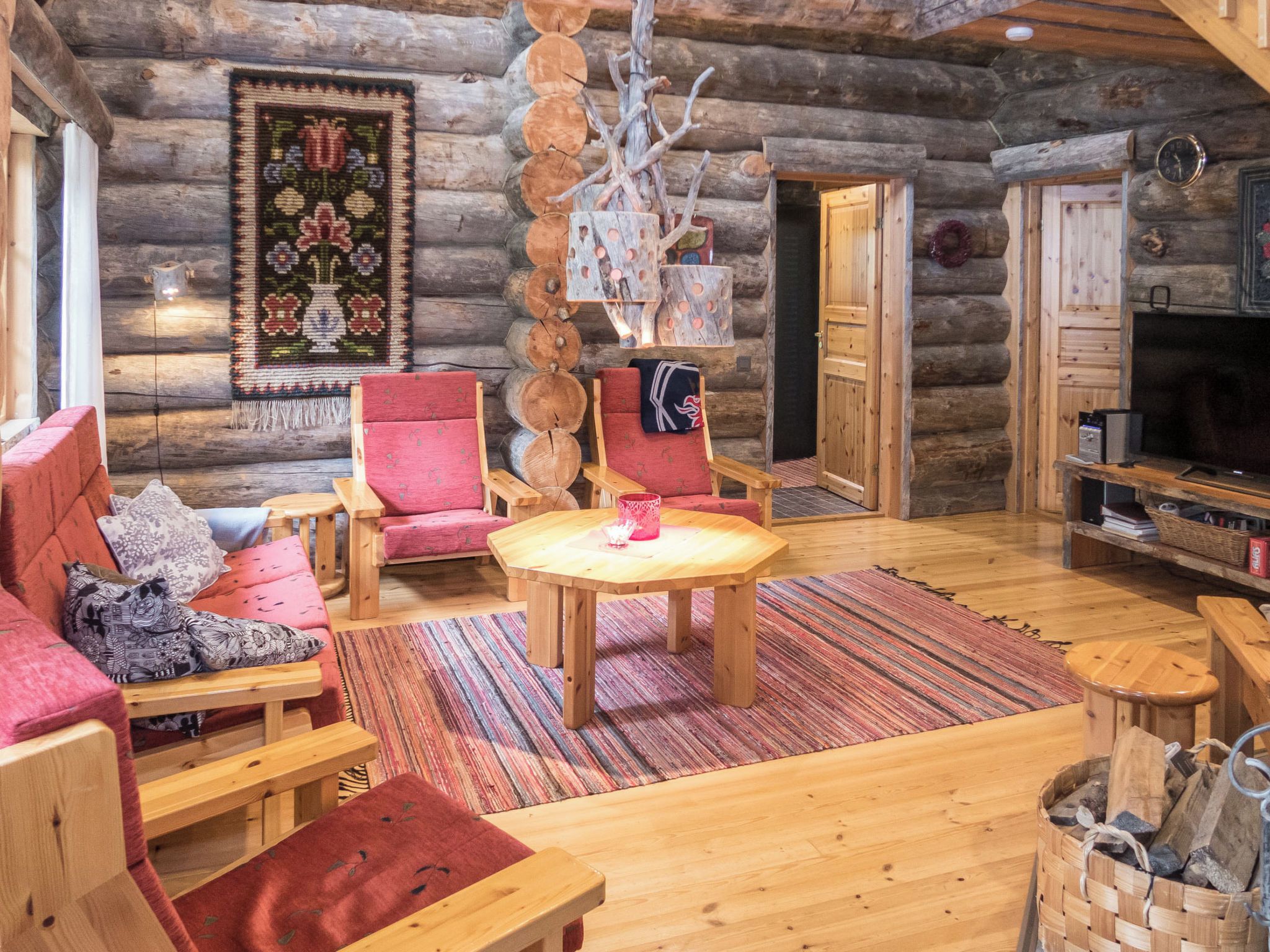 A log cabin interior with a cozy seating area, a wooden table, and a fireplace.