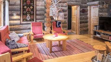 A log cabin interior with a cozy seating area, a wooden table, and a fireplace.