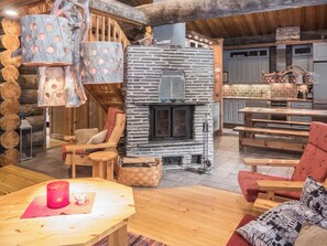 L’intérieur d’un chalet confortable, avec un foyer en pierre, des meubles en bois et un coin cuisine.