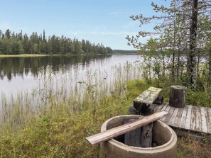 Un muelle de madera se extiende sobre un lago tranquilo, rodeado de un bosque denso y vegetación exuberante.