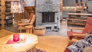 Ein gemütliches Blockhaus-Interieur mit Kamin aus Stein, Holzmöbeln und einer Küchenzeile.