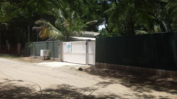 A gated area with a white gate, a fenced enclosure, and a small building with a sign. - El pasito is the place where you feel good at once (POTRERO)