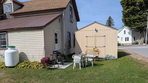 Une maison avec un garage, une pelouse et du mobilier d’extérieur.