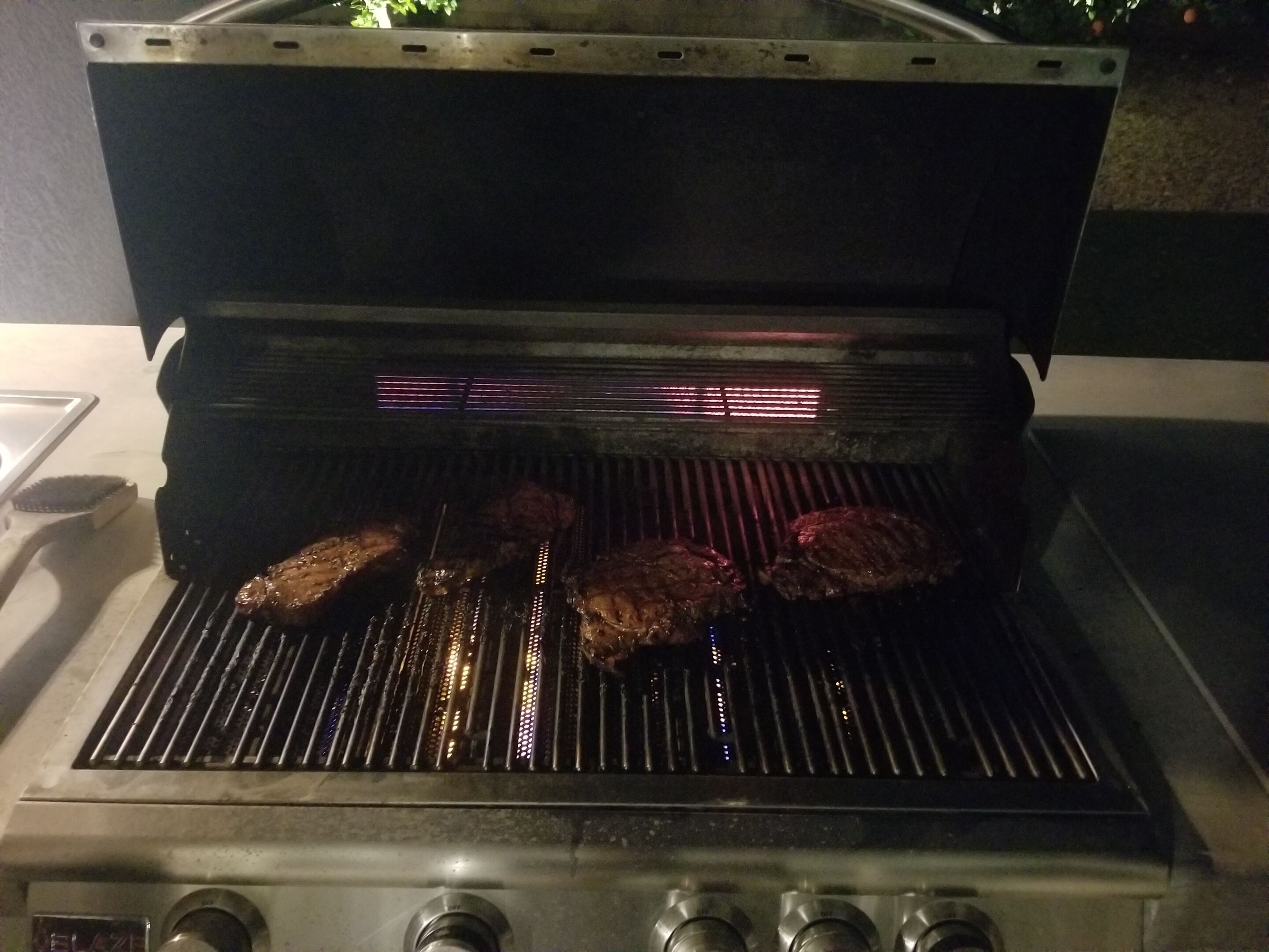 Een open barbecue met vlees dat gebakken wordt.