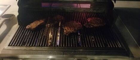 Een open barbecue met vlees dat gebakken wordt.