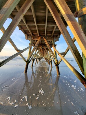 Una estructura de muelle de madera con una vista despejada de la playa y el océano al fondo.