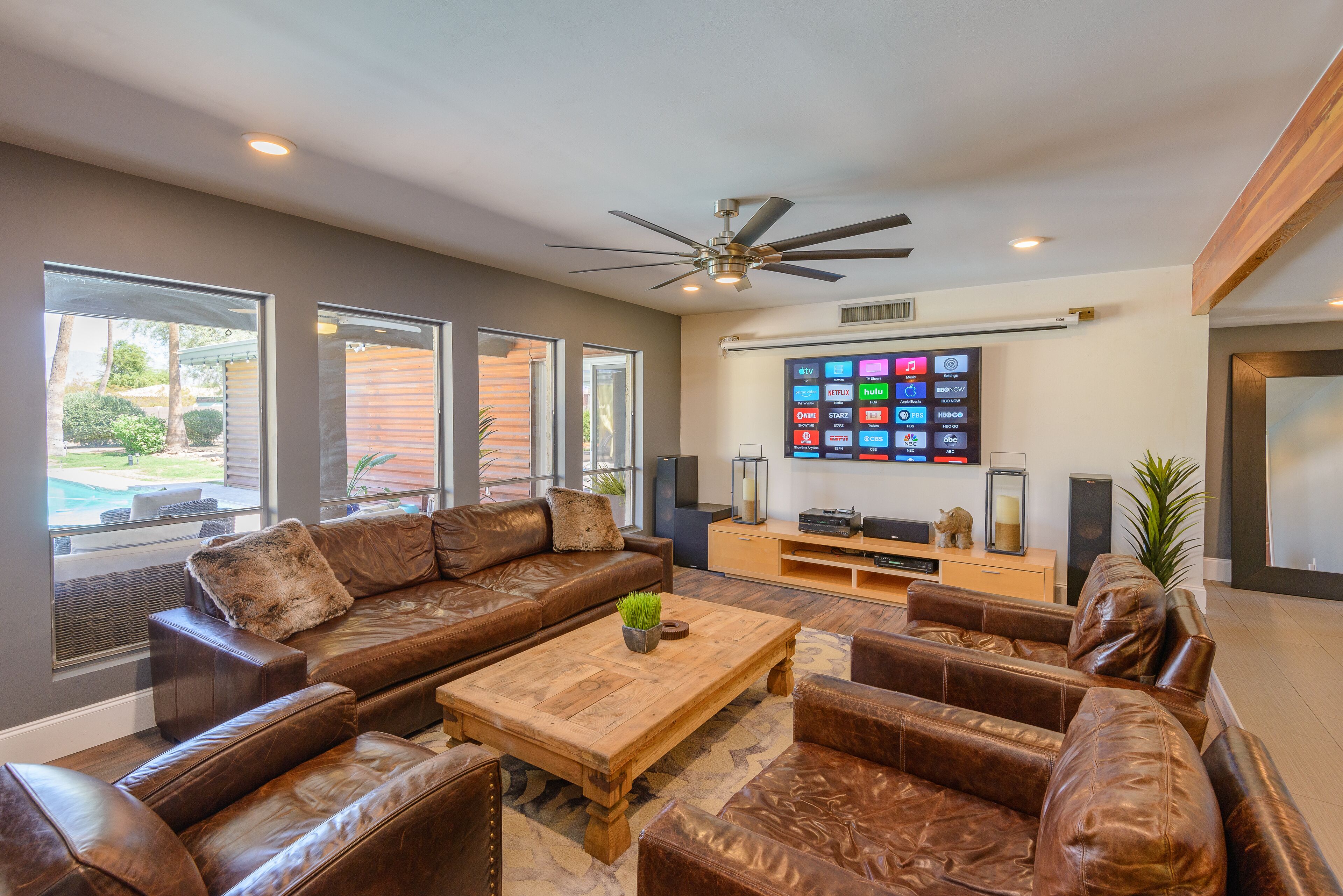 A modern living room with a sectional sofa, a wooden coffee table, and a flat-screen TV mounted on the wall.