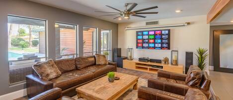 A modern living room with a sectional sofa, a wooden coffee table, and a flat-screen TV mounted on the wall.