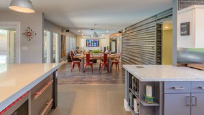 A modern kitchen with a dining area, featuring a large island with a marble countertop, red chairs, and a central dining table. - Most desirable neighborhood in Scottsdale.  2 masters, private 1 acre lot (Scottsdale)