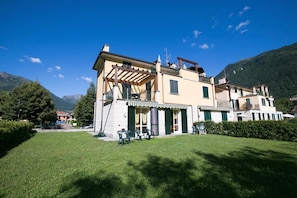 Un edificio a due piani con una pergola, posti a sedere all'aperto e vista sulle montagne.