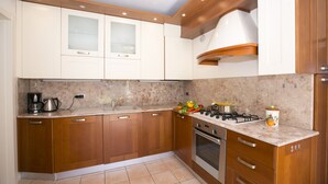 A modern kitchen with wooden cabinets, a gas stove, and a coffee maker. - Porto Letizia Mimosa 2, Porlezza, Italy (Porlezza)