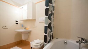 Une salle de bain équipée d’une baignoire, de toilettes, d’un lavabo et d’un miroir.