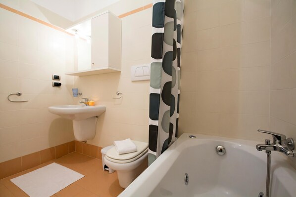 A bathroom with a bathtub, toilet, sink, and a mirror.