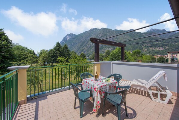A balcony with a table, chairs, and a sun lounger. - Porto Letizia Tulipano 7, Porlezza, Italy (Porlezza)