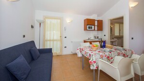 Un espace de vie compact comprenant un canapé, une table à manger, des chaises, un four à micro-ondes et un petit coin cuisine.