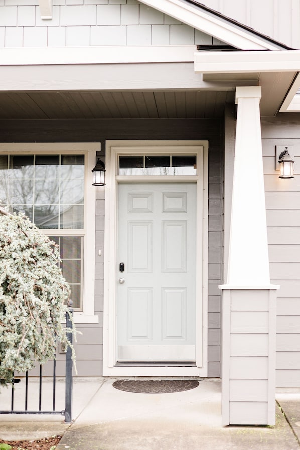 A house with a white front door, a small porch, and a window with a white frame.