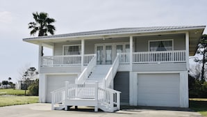 A two-story house with a covered front porch, a staircase, and a garage. - 
Cozy Waterfront Beach House with Private Beach/Pier/Tennis Courts (Pensacola)