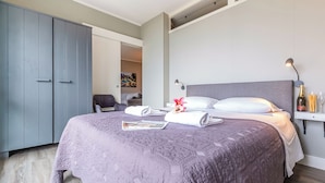 A modern bedroom with a large bed, a wardrobe, and a desk with a lamp. - Porto Letizia P8, Porlezza, Italy (Porlezza)