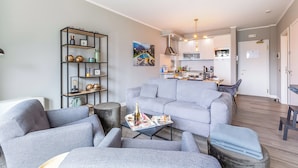 A modern living room with a grey sofa, a coffee table with magazines, and a bookshelf. - Porto Letizia P8, Porlezza, Italy (Porlezza)