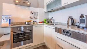 A modern kitchen with stainless steel appliances, white cabinetry, and a granite countertop. - Porto Letizia P8, Porlezza, Italy (Porlezza)