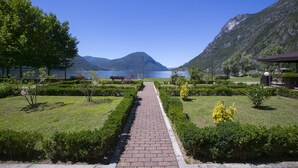 A paved pathway leading to a lake with mountains in the background. - Porto Letizia T14, Porlezza, Italy (Porlezza)