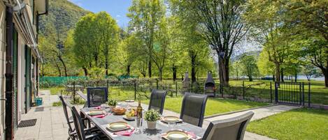 An outdoor dining area with a table set for four, surrounded by chairs, with a mountain and trees in the background.