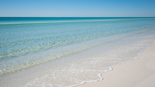 Ein Strand mit klarem türkisblauem Wasser und weißem Sand.