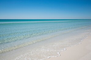 Ein Strand mit klarem türkisblauem Wasser und weißem Sand.