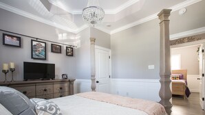 A bedroom with a large bed, a television on a dresser, and framed pictures on the wall. - Beautiful City View GEM of NOLA, Vacation Luxury! (New Orleans)