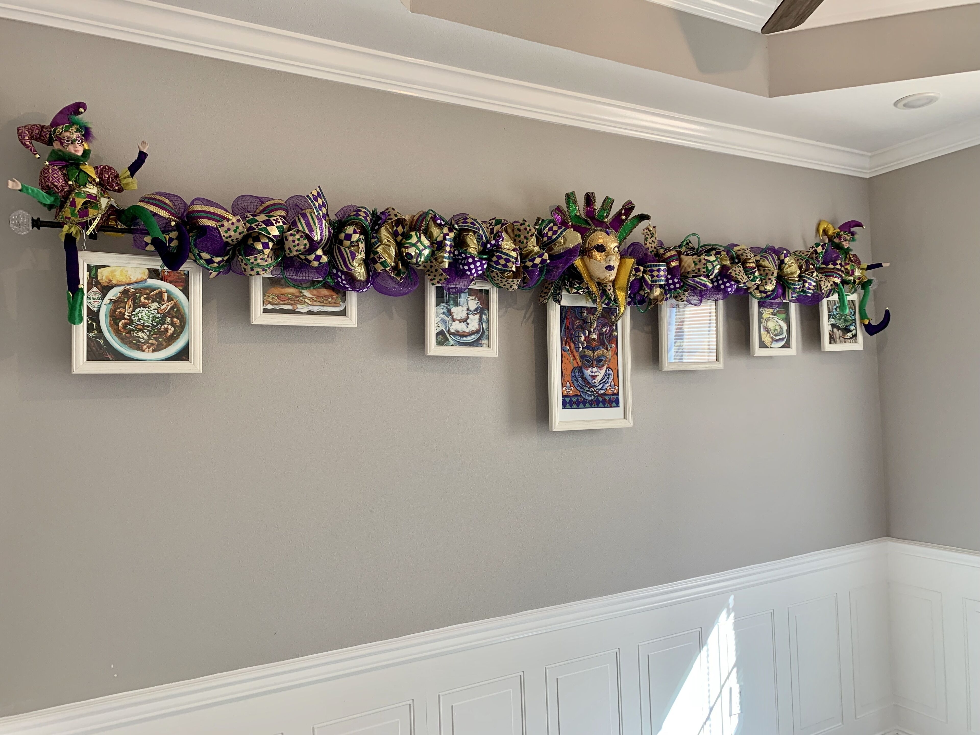 Un couloir décoré d’une guirlande ornée de masques et de tableaux encadrés.