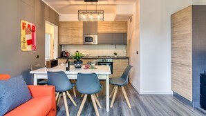A modern kitchen with a central island, wooden cabinets, and a microwave. - Porto Letizia Orchidea 2, Porlezza, Italy (Porlezza)