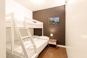 Quarto com beliche, mesa de cabeceira e abajur.