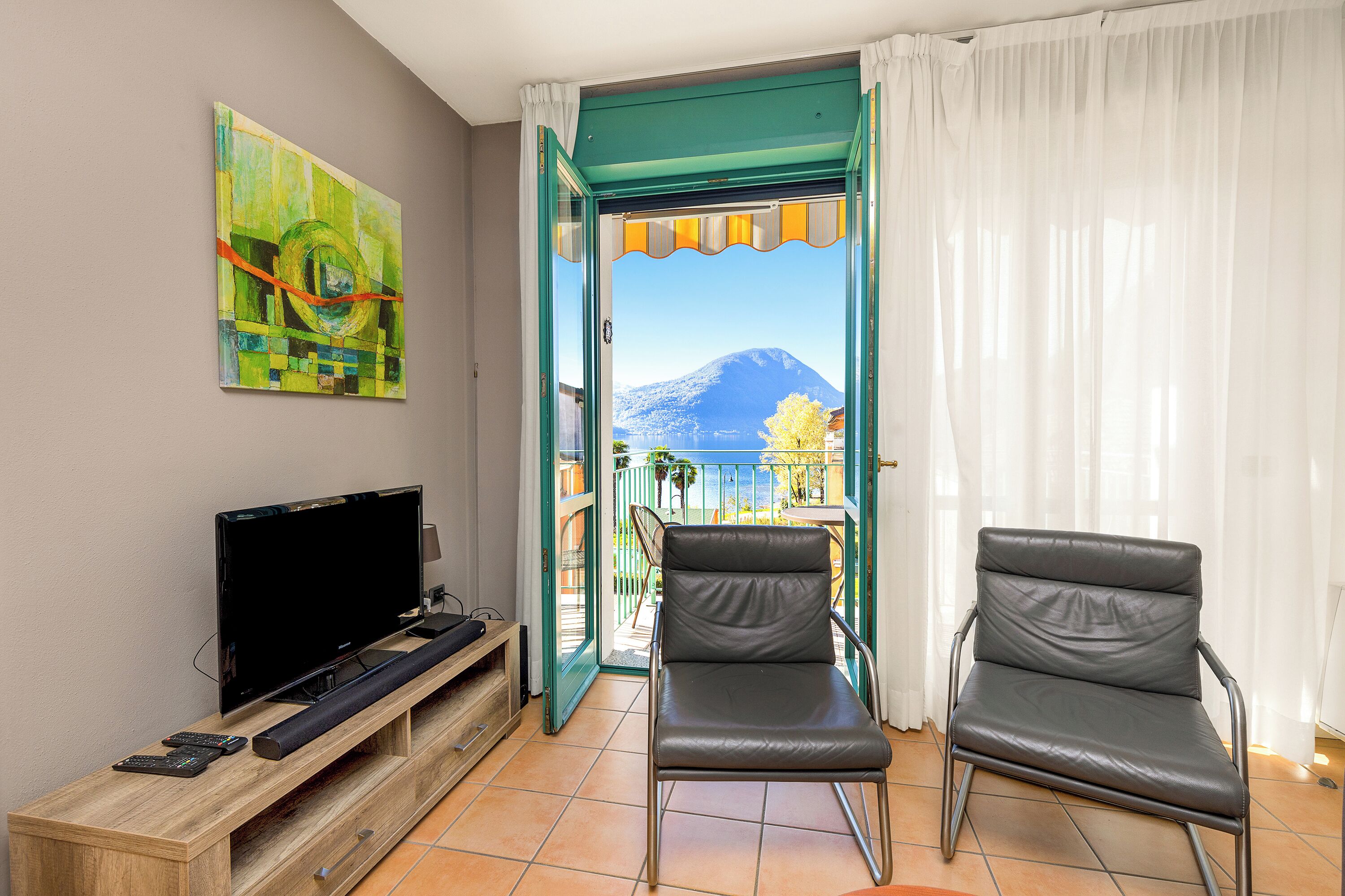 A room with a TV, a chair, and a painting.