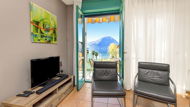 A room with a TV, a chair, and a painting. - Porto Letizia S5, Porlezza, Italy (Porlezza)