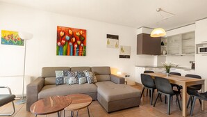 A modern living room with a sectional sofa, a dining table with chairs, and a kitchen area. - Porto Letizia S5, Porlezza, Italy (Porlezza)