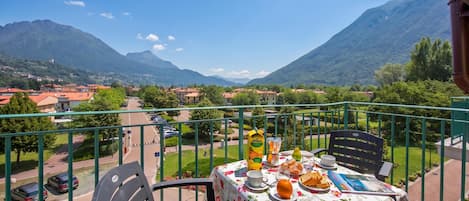 A balcony with a table set for breakfast, overlooking a mountainous landscape.