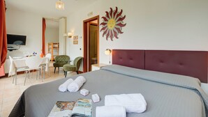 A hotel room with a large bed, a desk, and a chair.