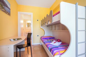 A compact room with a bunk bed, a desk with a chair, and a small bathroom visible through an open door.