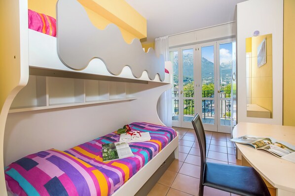 Una habitación con literas, una mesa de comedor y vistas a las montañas a través de puertas de cristal.