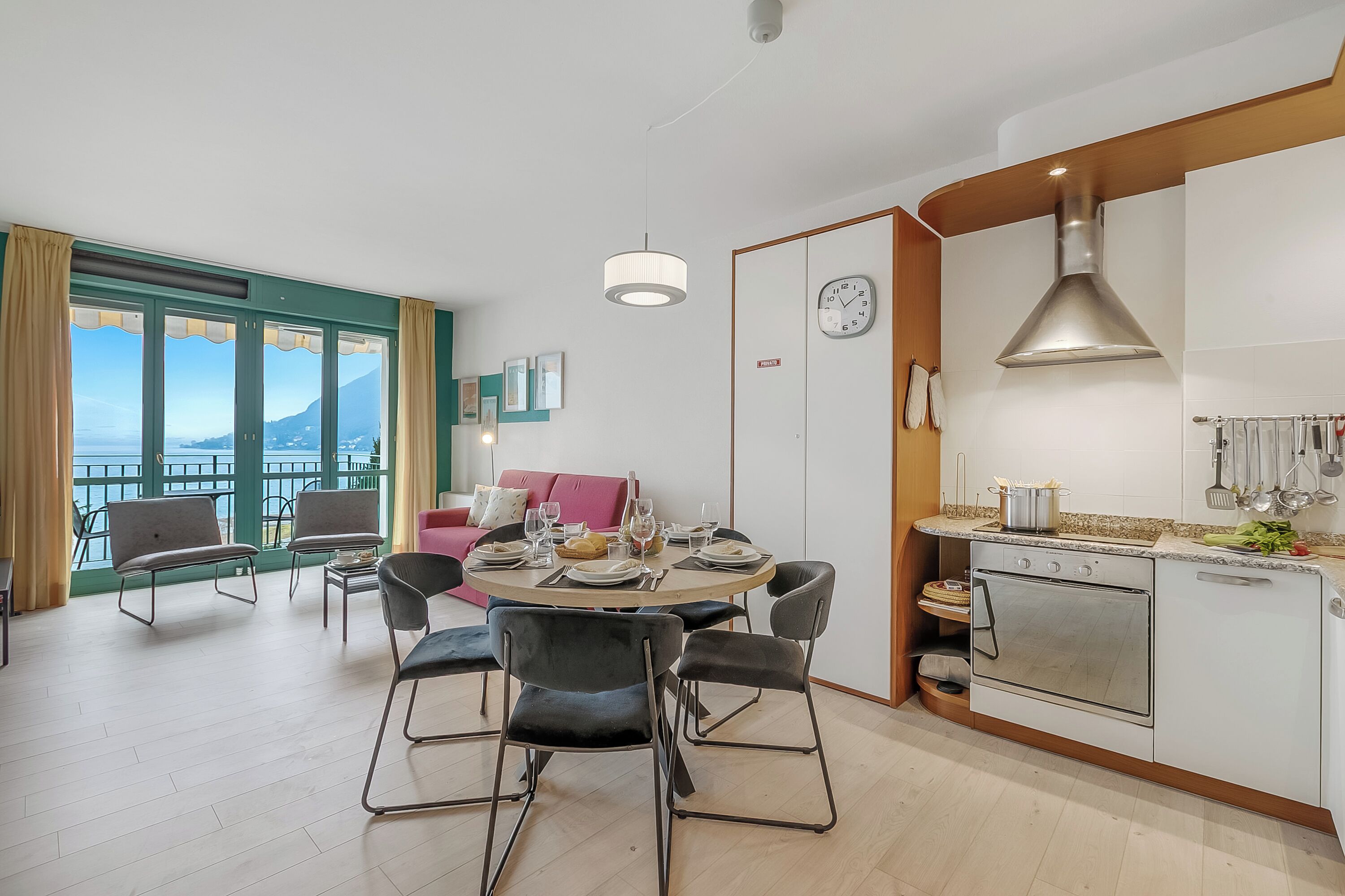 Una cocina moderna con horno integrado, mesa de comedor con sillas y vistas a un balcón.