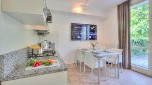 A modern kitchen with a gas stove, a dining table with chairs, and a large window with curtains. - Porto Letizia Ortensia 3, Porlezza, Italy (Porlezza)