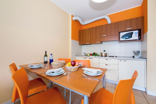 Une cuisine moderne avec des chaises orange, une table en bois et un four à micro-ondes.